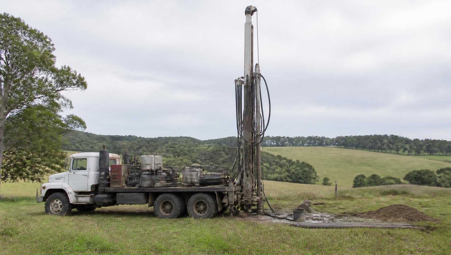 Water well drilling rig set up on a rural grass property